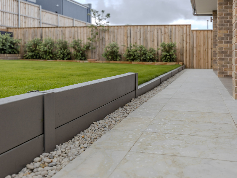 Integrated drainage system for a landscaped backyard with paving and retaining walls.