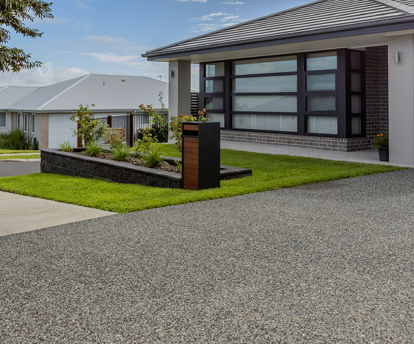New exposed aggregate driveway installed at a modern residential home.