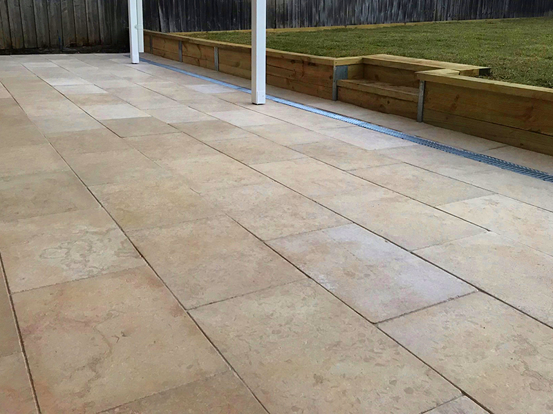 Natural stone paved outdoor entertaining area with retaining wall and drainage.